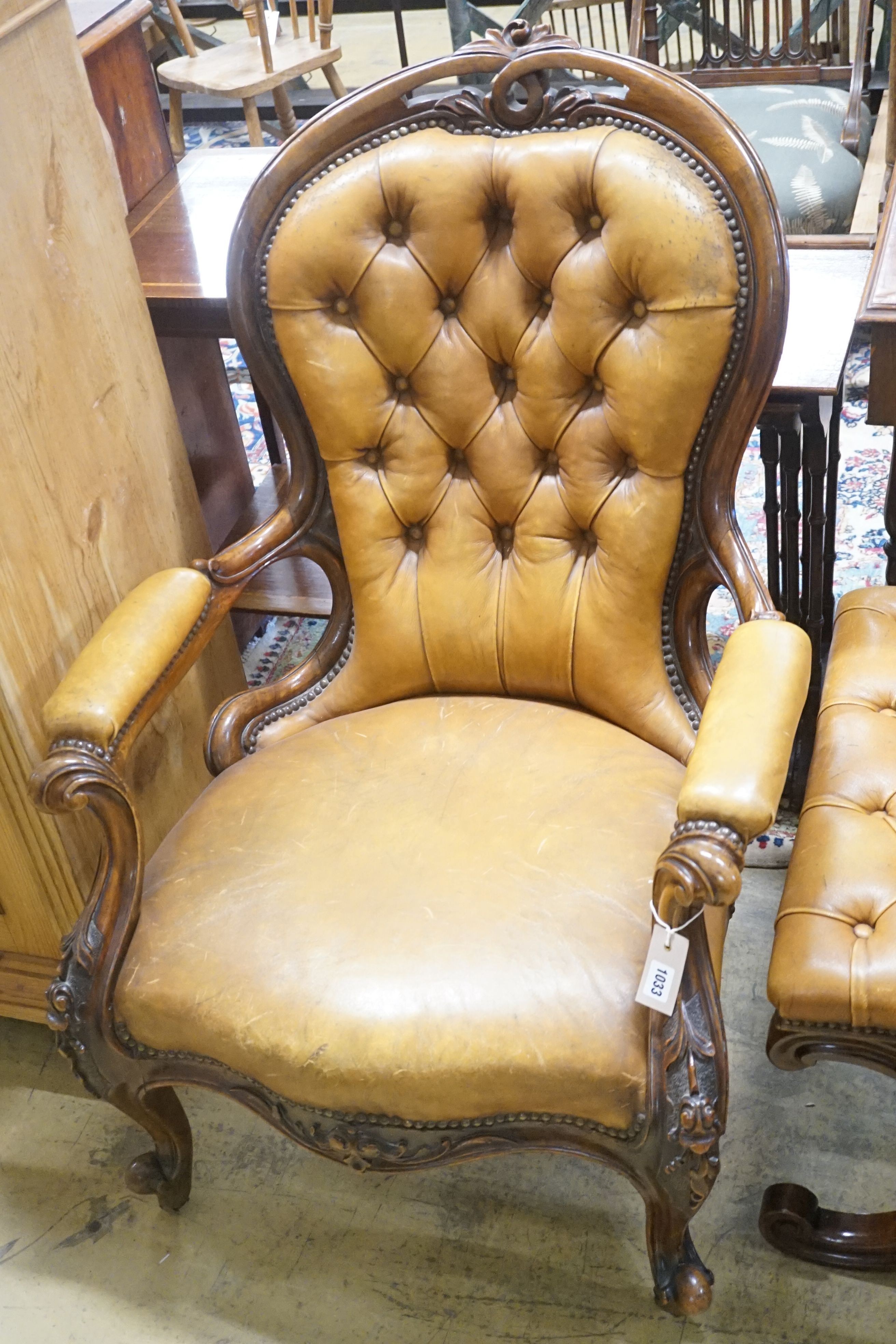 A Victorian carved walnut spoonback open armchair, upholstered in buttoned brown leather, width 69cm depth 66cm height 99cm